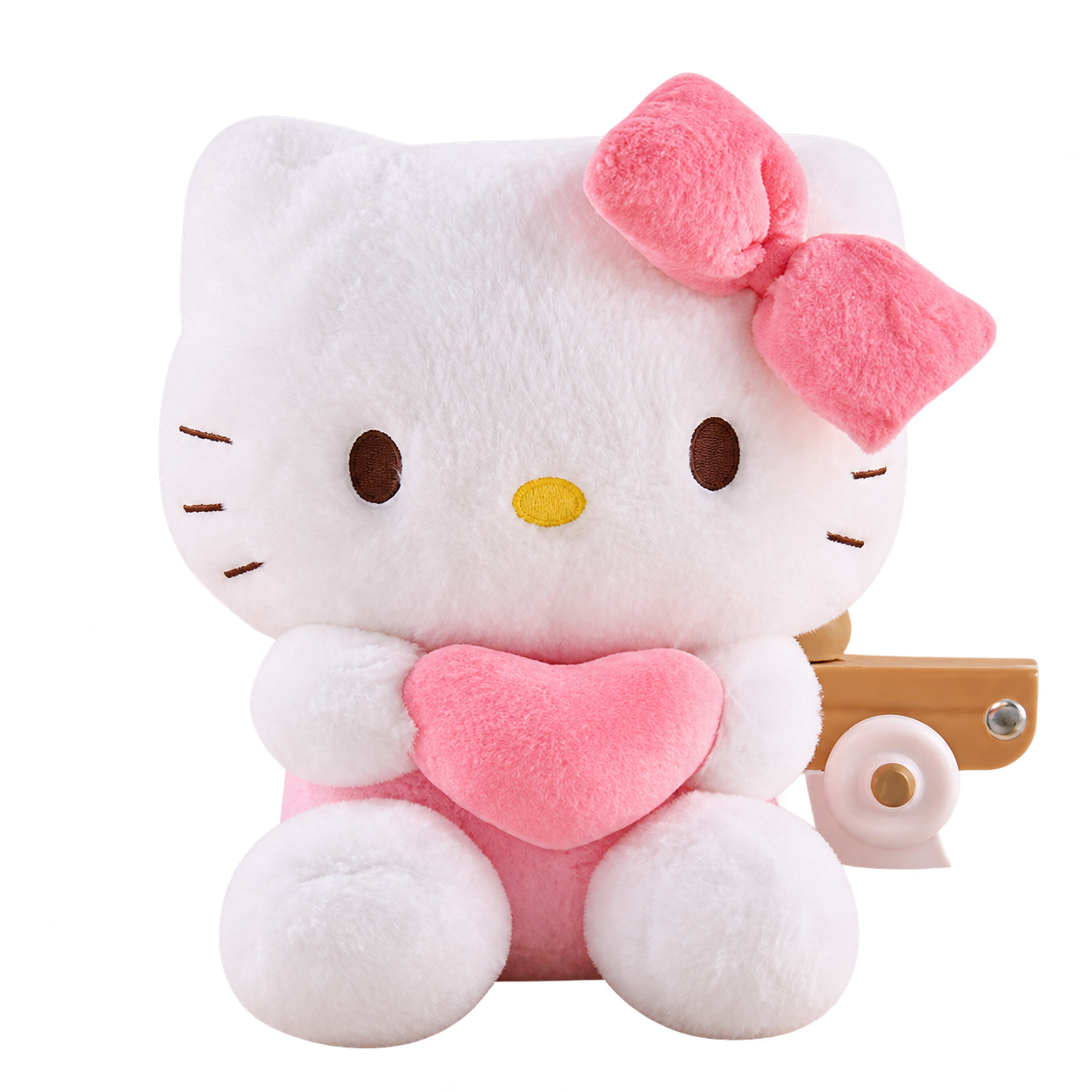 A white Kitty plush holding a pink heart, with a pink bow, brown embroidered eyes and whiskers, a yellow nose and pink lower body.